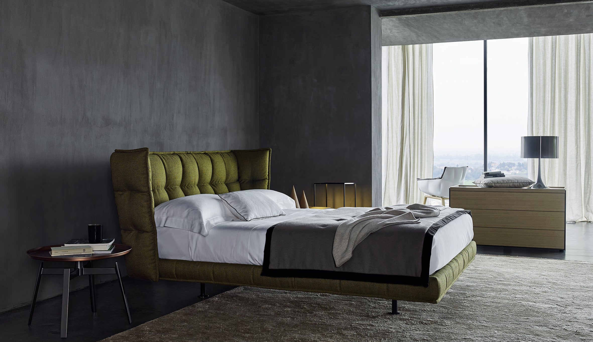 Modern bedroom with a green upholstered bed and large windows.