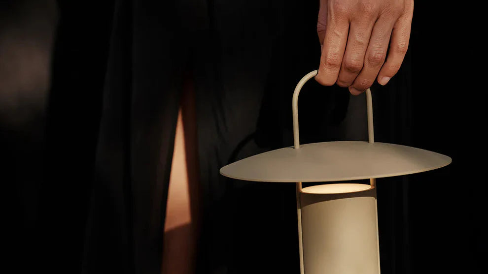 Hand holding a modern lantern against a dark background