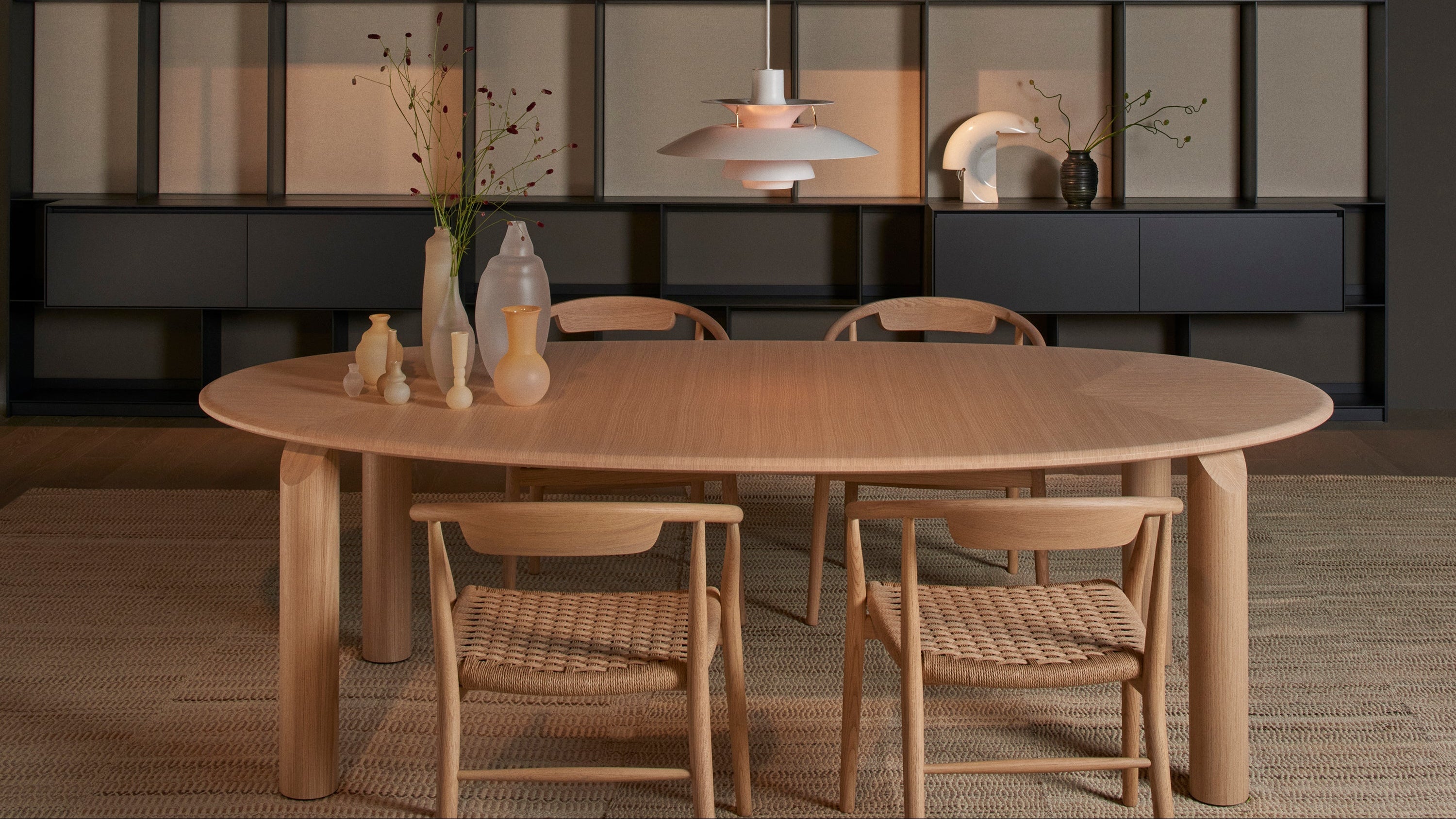 Dining area with wooden table and chairs in front of a bookshelf.