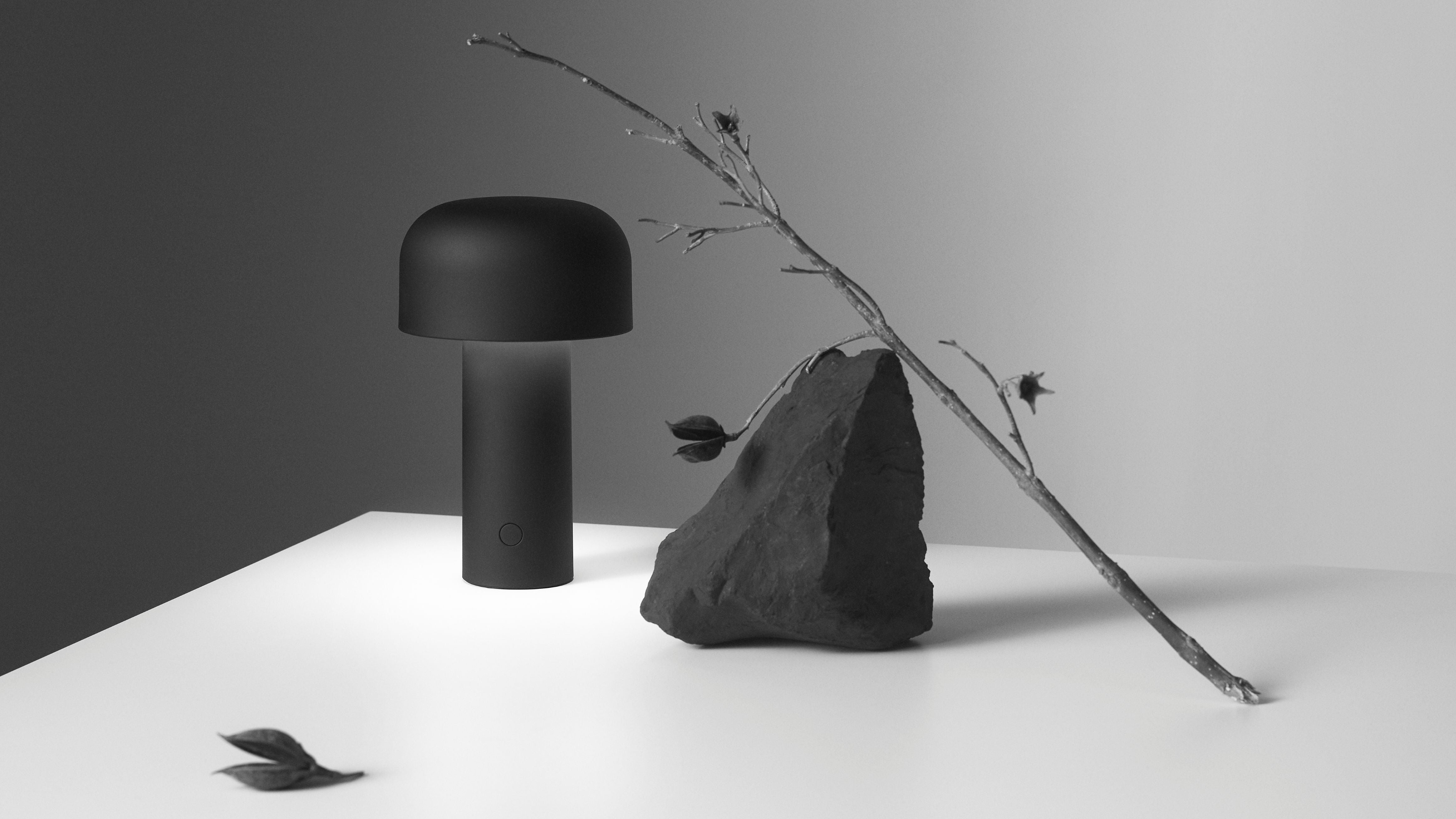 Black lamp and stone on a white surface with a gray background