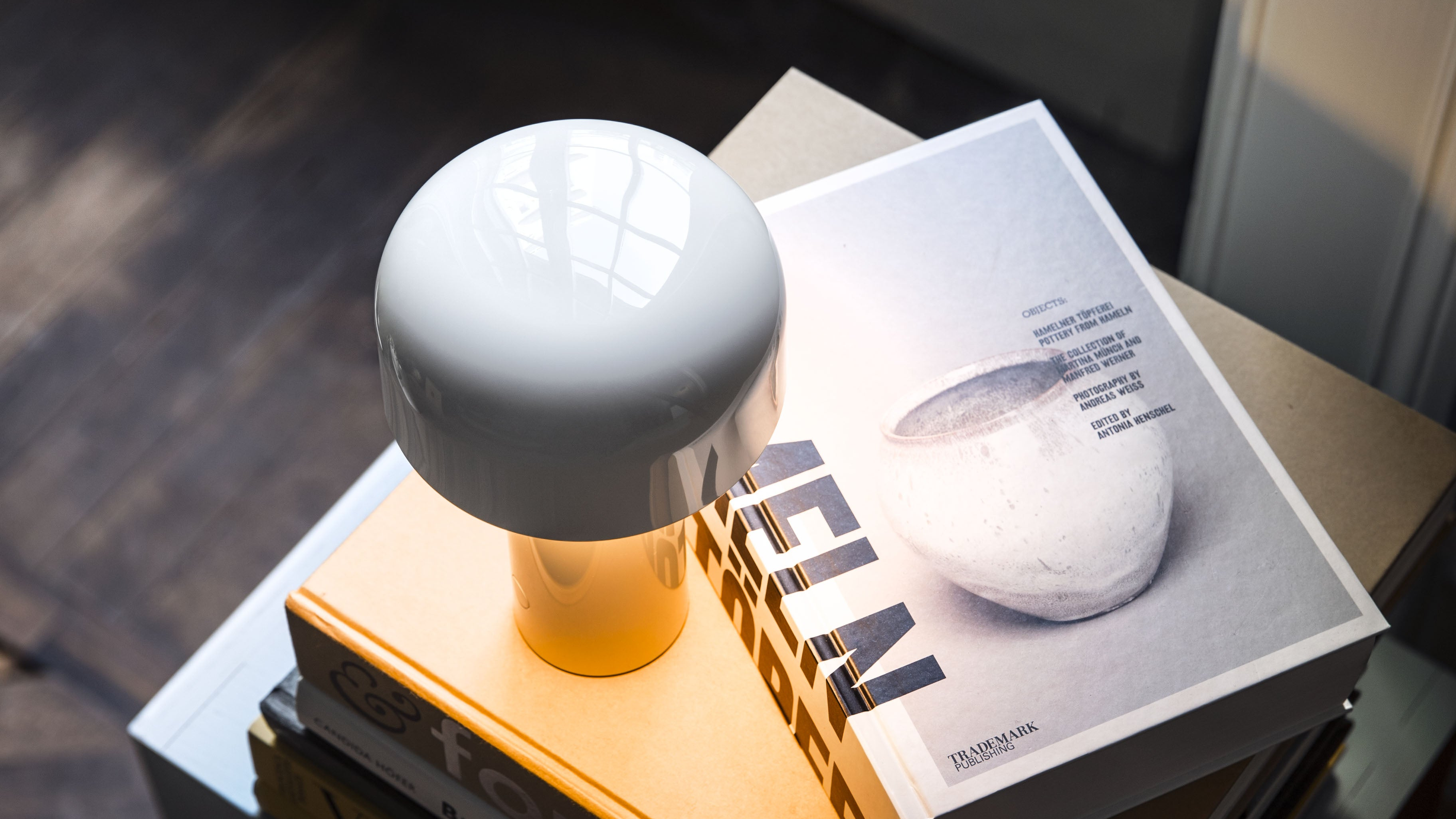 White spherical table lamp on a wooden surface with a magazine underneath