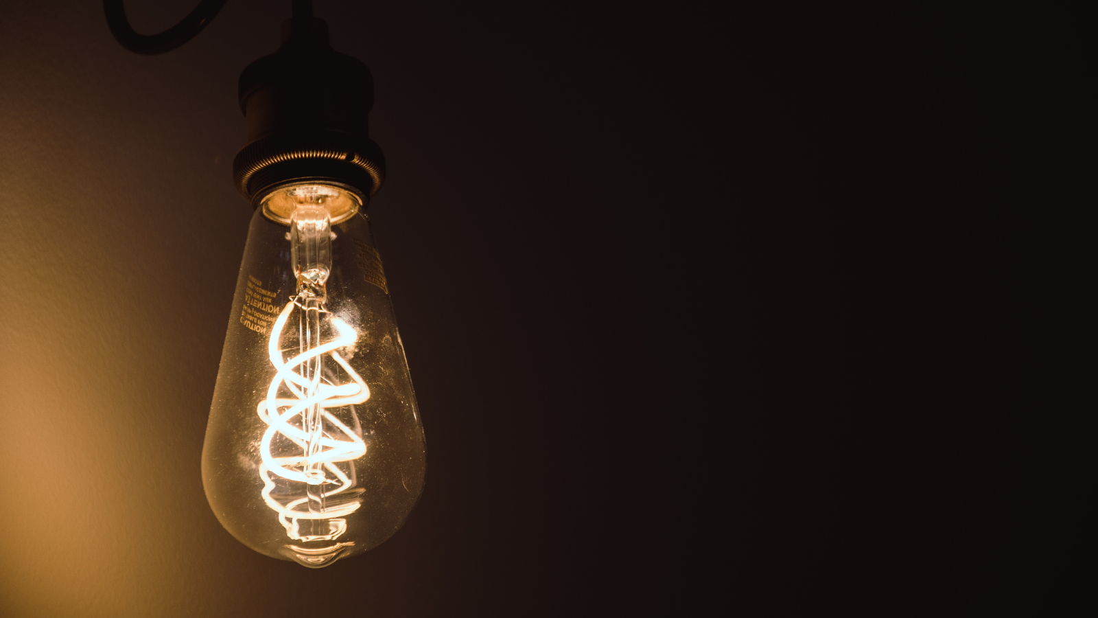 Vintage-style light bulb with a coiled filament against a dark background