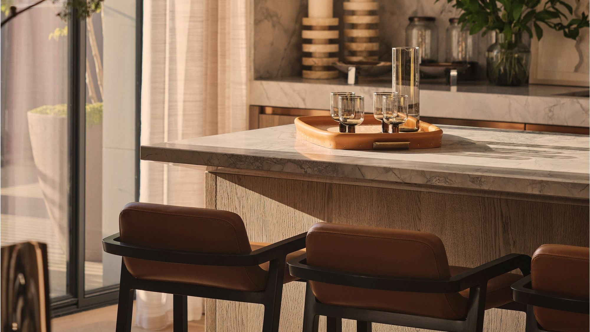 Modern kitchen with marble island, bar stools, and decorative elements.