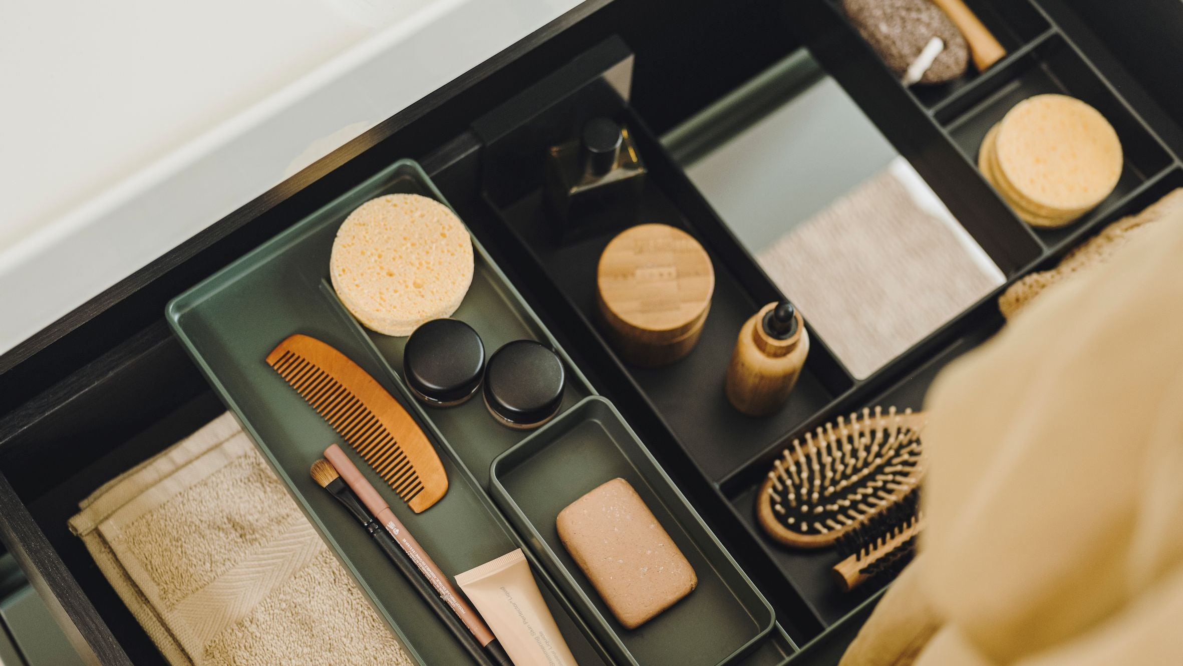 Makeup organizer with various cosmetic items including a comb and bottles on a white surface.