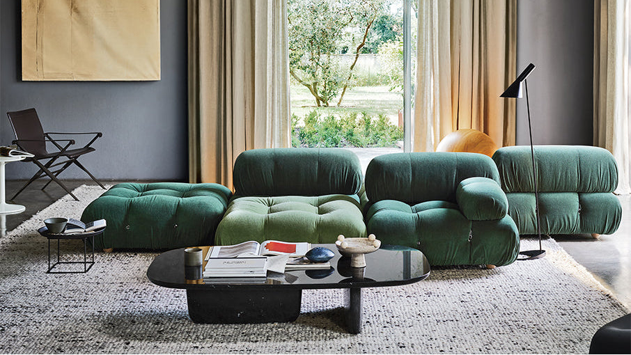 Modern living room with a green sectional sofa, coffee table, and decorative items.