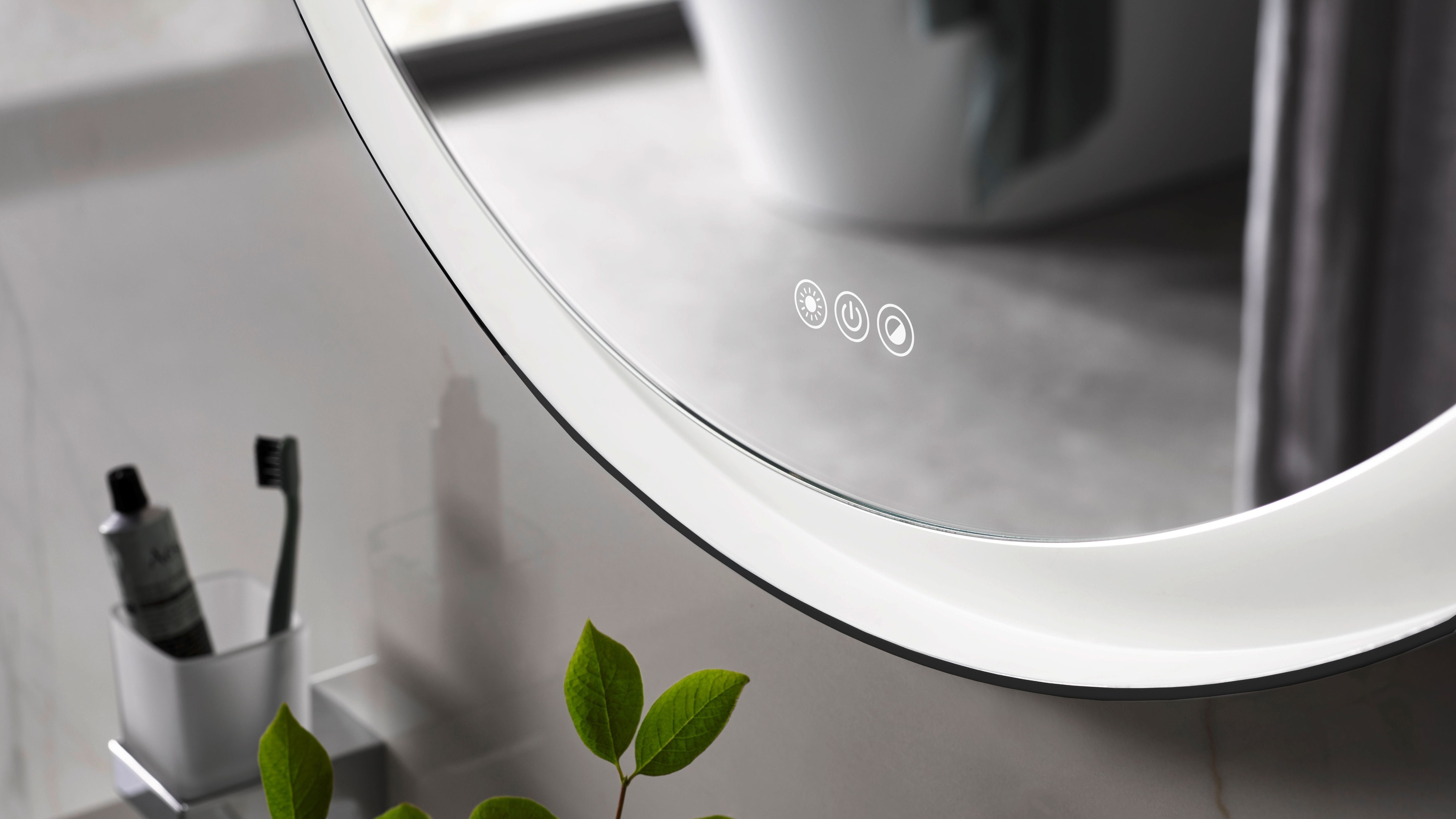 Round bathroom mirror with control buttons reflecting a blurred bathroom setting.