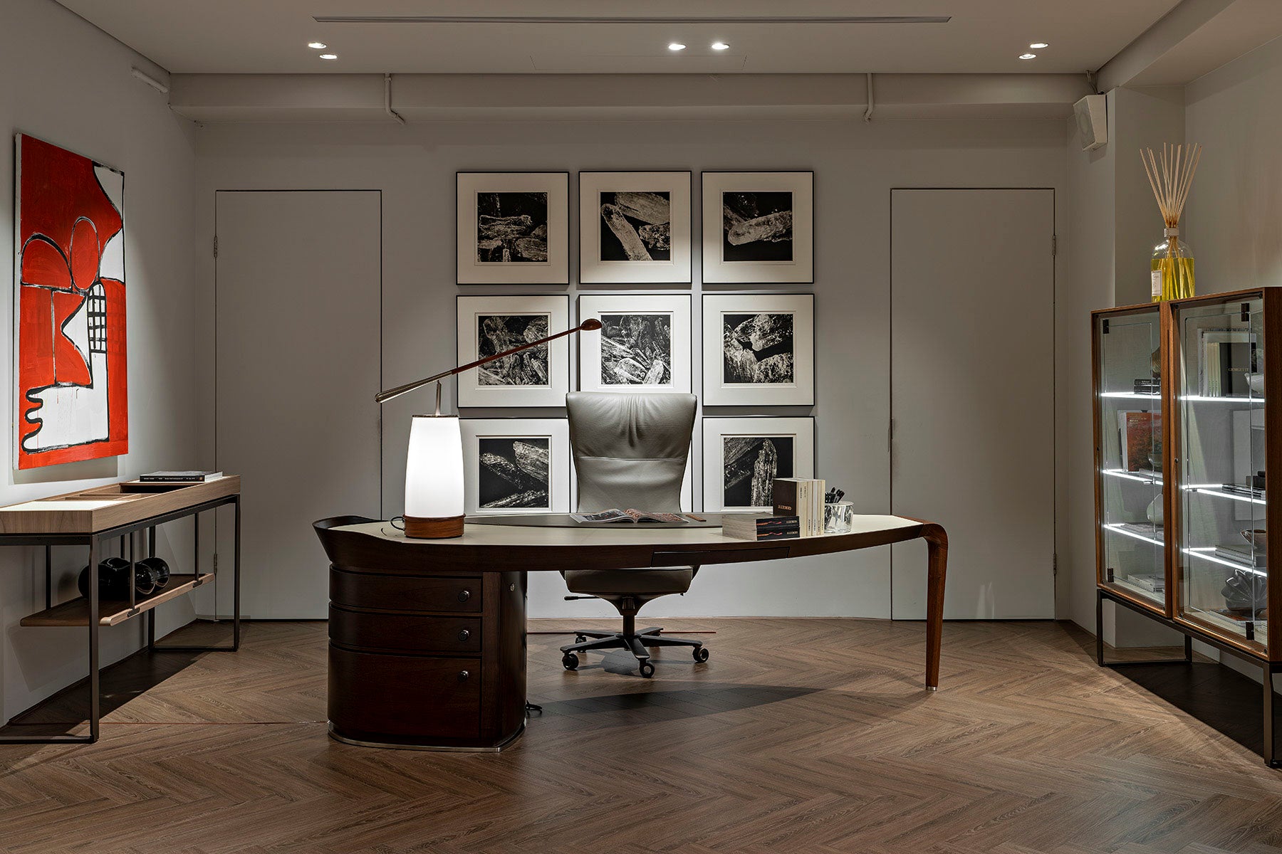 Modern office interior with a desk, lamp, and framed pictures on the wall.