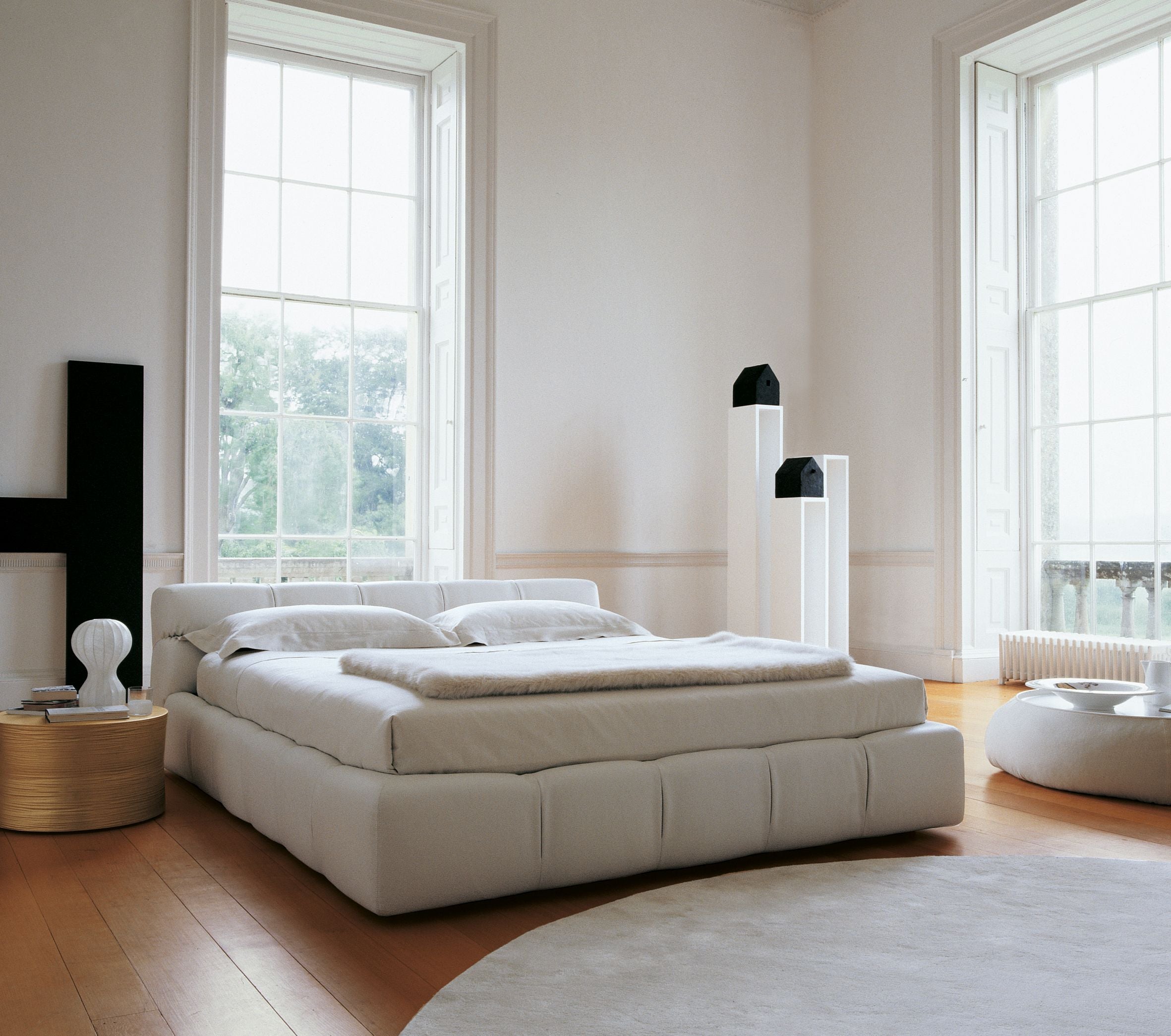 Modern bedroom with a large bed, side tables, and large windows.